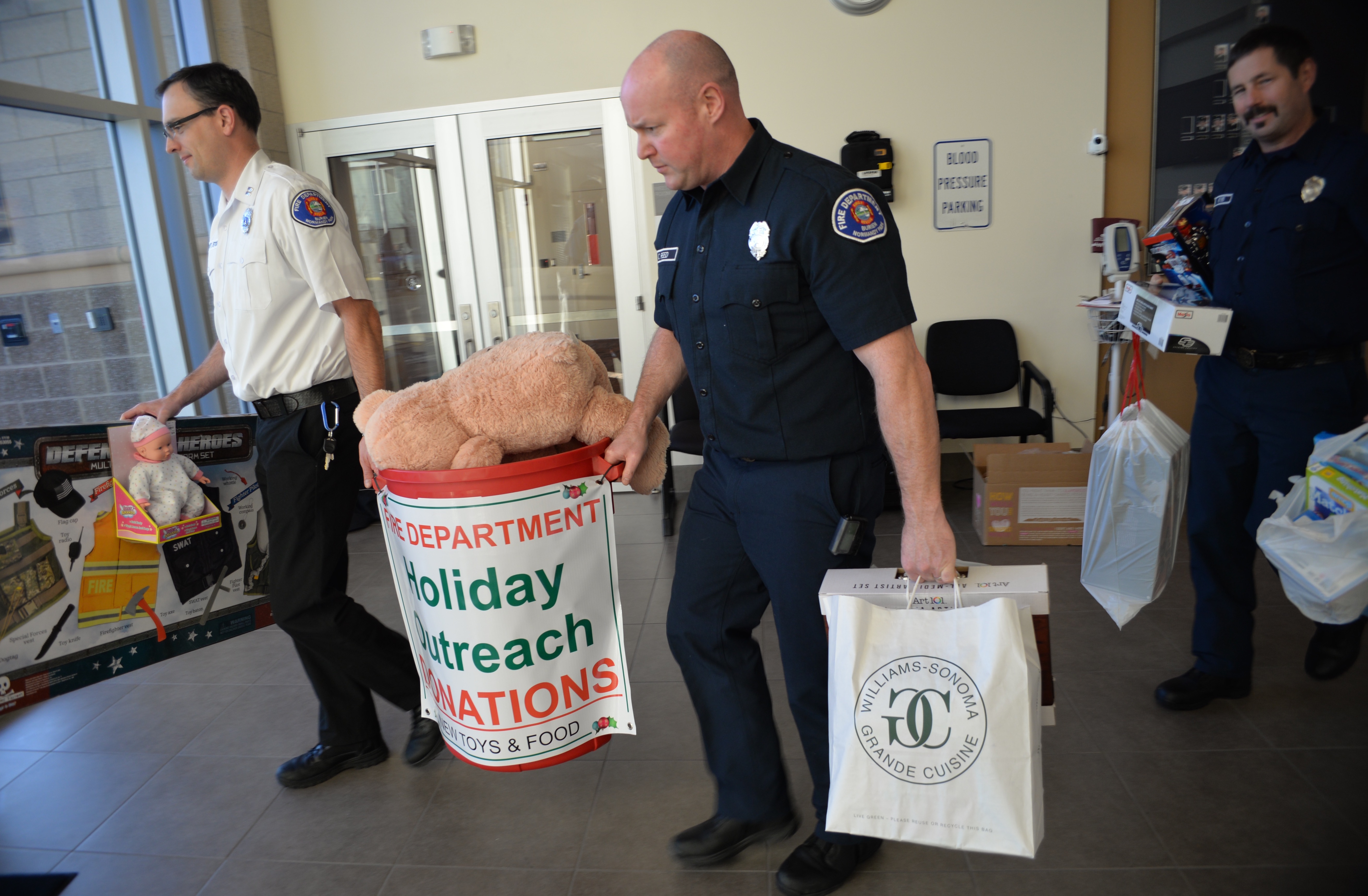 Capt. George Stoess, fire inspector, and firefighters Chris Reed and Allen Keyes, load up donations from their bin in preparation of sorting the toys by age. 