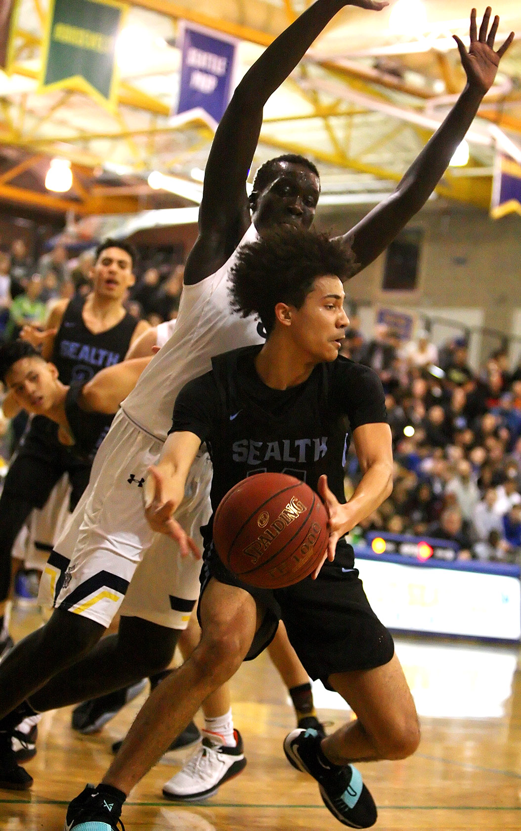 Sadique Calloway of Chief Sealth ties to get away from the outstretched arms of West Seattle Maar Rambang. 