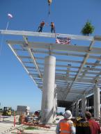 Two ironworkers shake hands after placing the final main beam on Sea-Tac Airport's rental car facility.