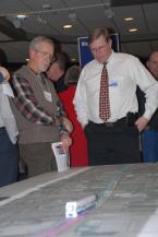 A paper model of a light-rail train  sits on the map of the proposed new route while workshop participants talk.