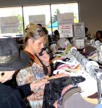 A woman shopper looks over clothing while talking on her cell phone DM Goodwill 2.jpg
