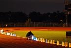 A man bends down to place a luminaria along the track. Photo by Patrick Robinson DSC_5781.jpg