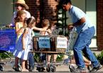Kids donate to the Des Moines Area Food Bank as workers push makeshift shopping carts up the parade path.