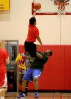 Alumni player Anthony Summers of Tyee takes it to the basket as an Evergreen player blocks his way.