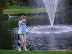 Pirates' golfer, Jacqueline Kemp, dropping a new ball, per golf rules, arm-outstretched,  of having just put a ball in the water, at the Auburn Golf Course of the Seamount  League Golf Tournament.