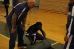 Foster coach, Patrick Kalalau, watching over Shakila Omar as she tightly rolls up one  of the under-mats that help keep the regular size mats in place during a wrestling  match like this one that just ended against the Lindbergh Eagles.